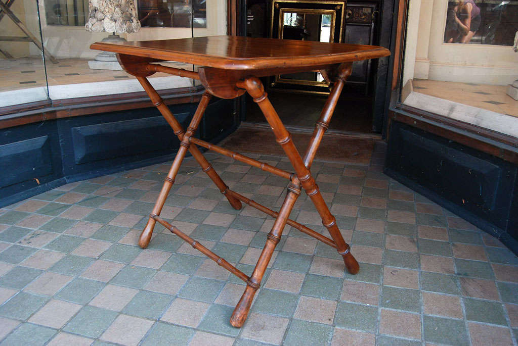 A charming and useful folding late 19c table with turned faux bamboo legs and stretchers and a lovely generous molded edge top of walnut with the original finish.