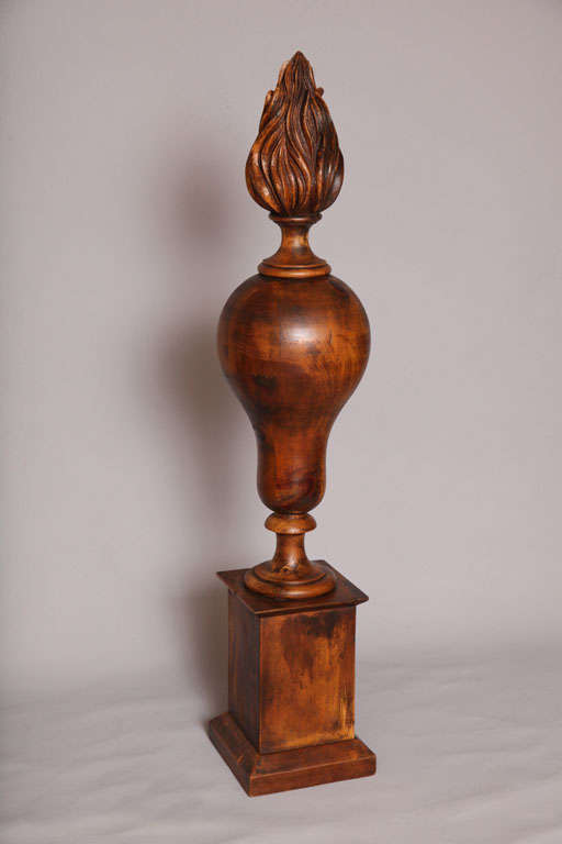 Large finial, of walnut, carved as flame-topped urn on square plinth.  By Chapman.<br />
<br />
(Keywords: Carving, Flame, Architectural, Fragment)