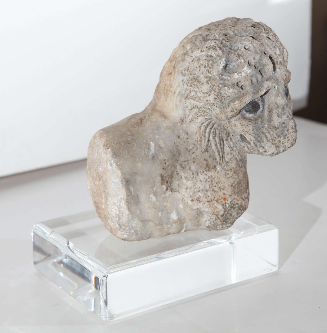 Carved, marble lion head with lead eyes, originally part of a column support.