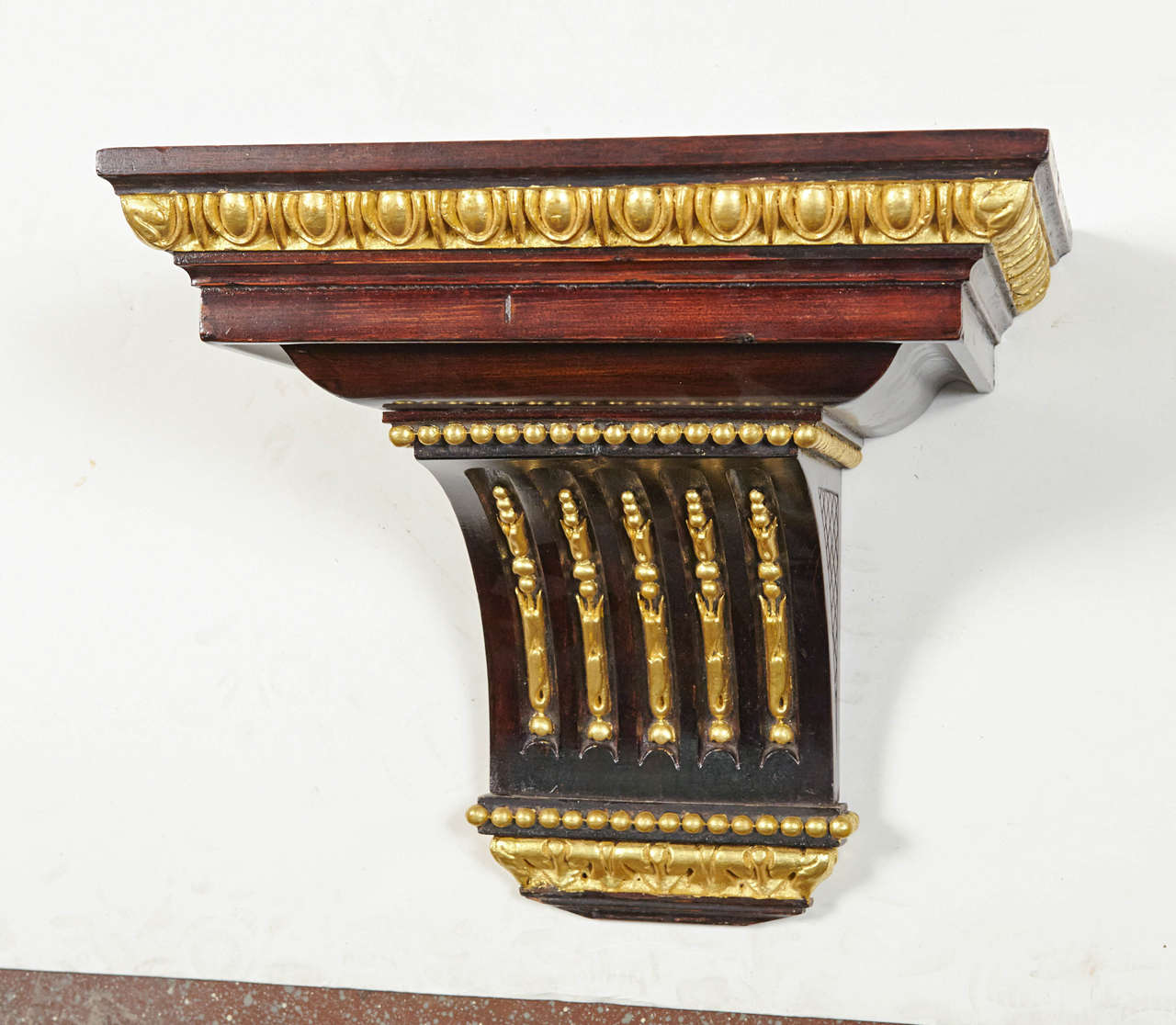 Regency-style mahogany stained wall bracket with gilded gadroon edge detail on stacked shelf, gilded bellflowers and beading.
