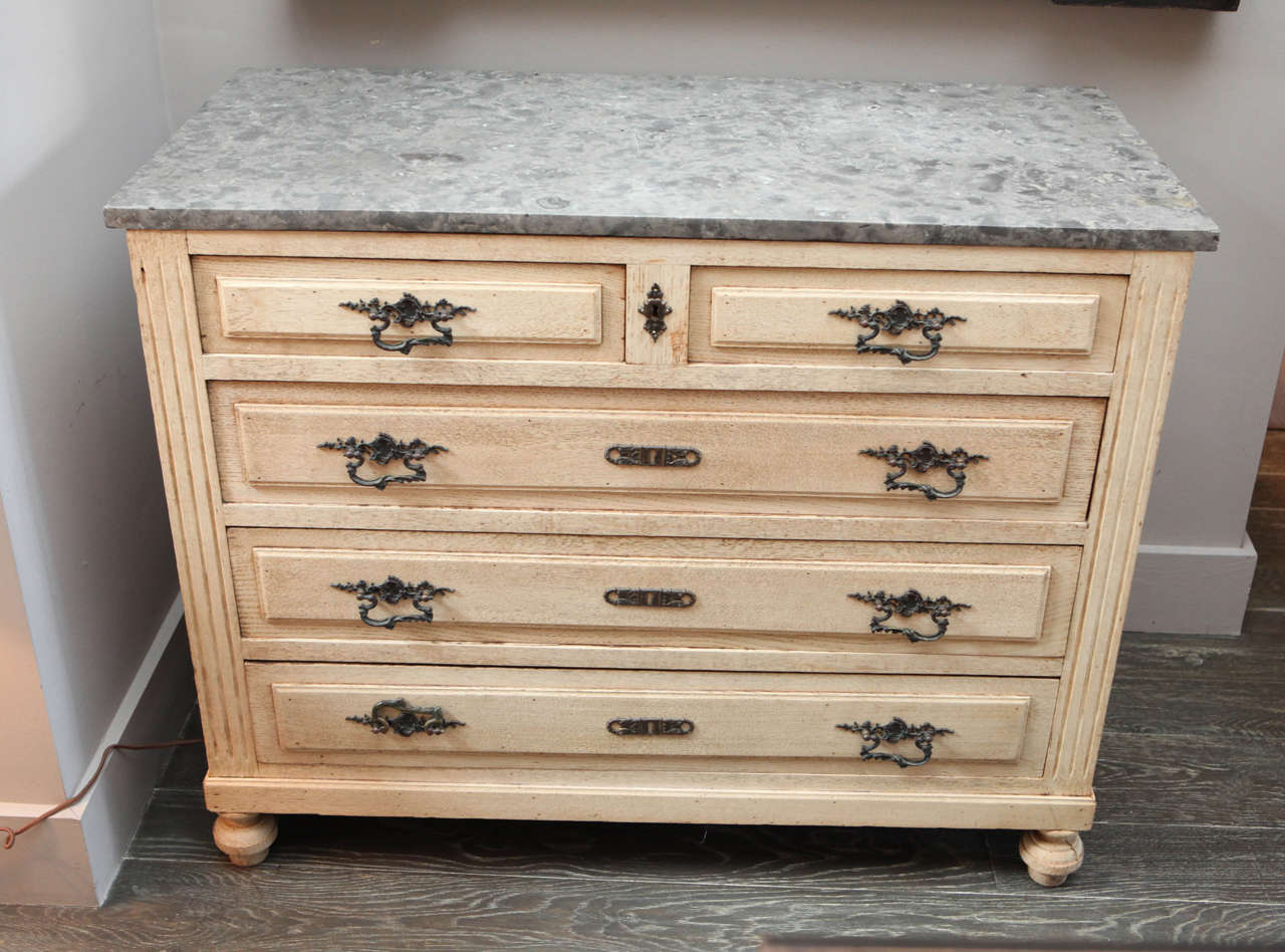 A bleached oak chest of drawers with grey marble top, circa 1900.