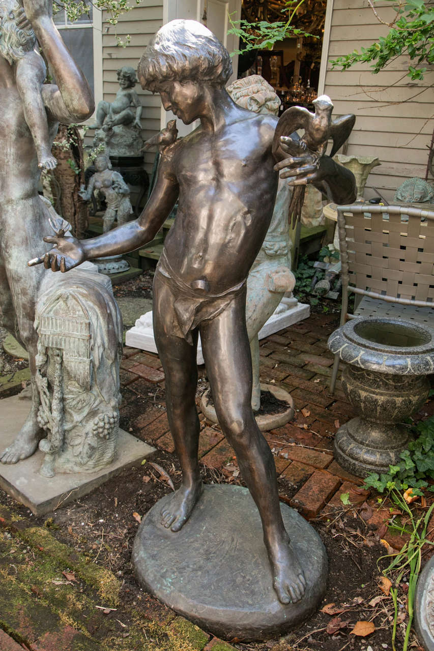 Based on a classical form, this dark brown patinated bronze depicts a youth wearing a loin cloth. On his right shoulder sits a bird. On his outstretched right hand another bird sits. His right hand holds a bird with a long tail and outstretched