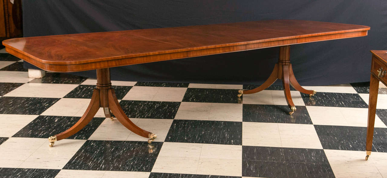 Absolutely stunning, swirled mahogany graces the top of this two-pedestal, two-leaf, classically styled dining table. Banded in straight grain mahogany with a delicate stringing of boxwood and ebony and featuring a beaded apron, this table is able