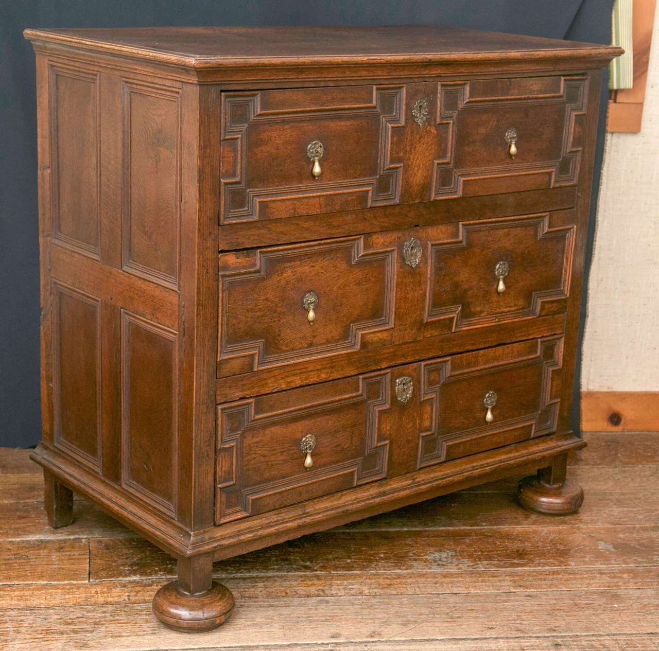 Constructed at the height of England’s love affair with oak, this three drawer chest displays all the features associated with the design of the era. A deeply molded top, geometric panels on the drawer fronts on drawers with side runners and