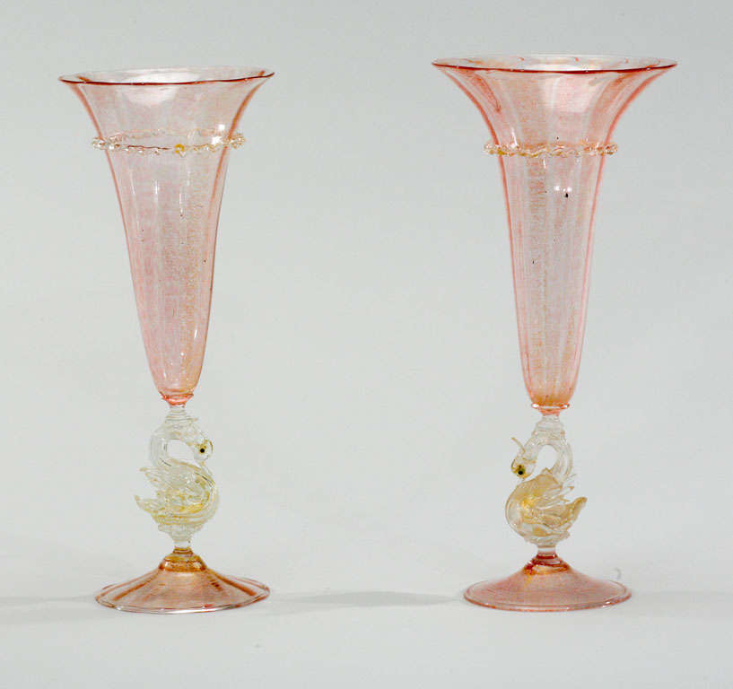 Beautiful pair of handblown tall trumpet vases with mottled pink and gold ground and applied rigaree of clear glass with gold leaf inclusions. The gold embellished swan connectors are well defined and gracefully executed. Each is hand blown and