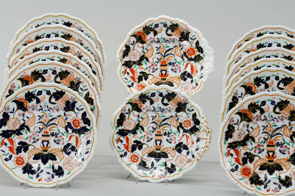 This lovely set of 12 hand painted plates in primary bold colors on a clean white ground which provide a dramatic contrast. The set also includes 2 matching shell shaped serving pieces which are both decorative and useful. These would create a