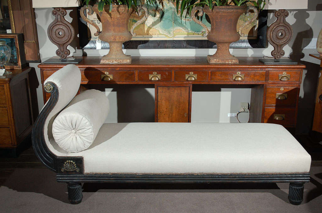 The elegant curved end is mounted with a brass flower medallion, studs and anthemion. The day bed or lounge upholstered in Belgian linen raised on twist reeded legs.