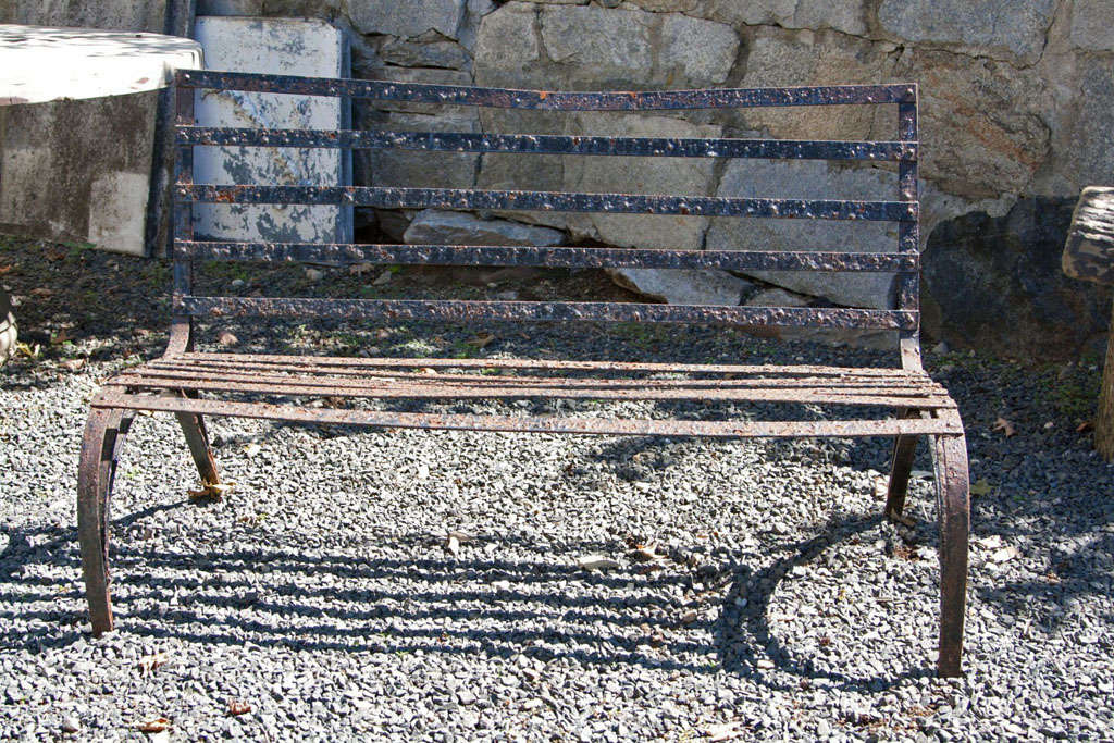 This black wrought iron bench with its rare form, curved legs and beautifully-aged surface, would make a statement placed on a gravel path in a garden or moved indoors to a modern sunroom. Good condition, with age appropriate surface, it is all