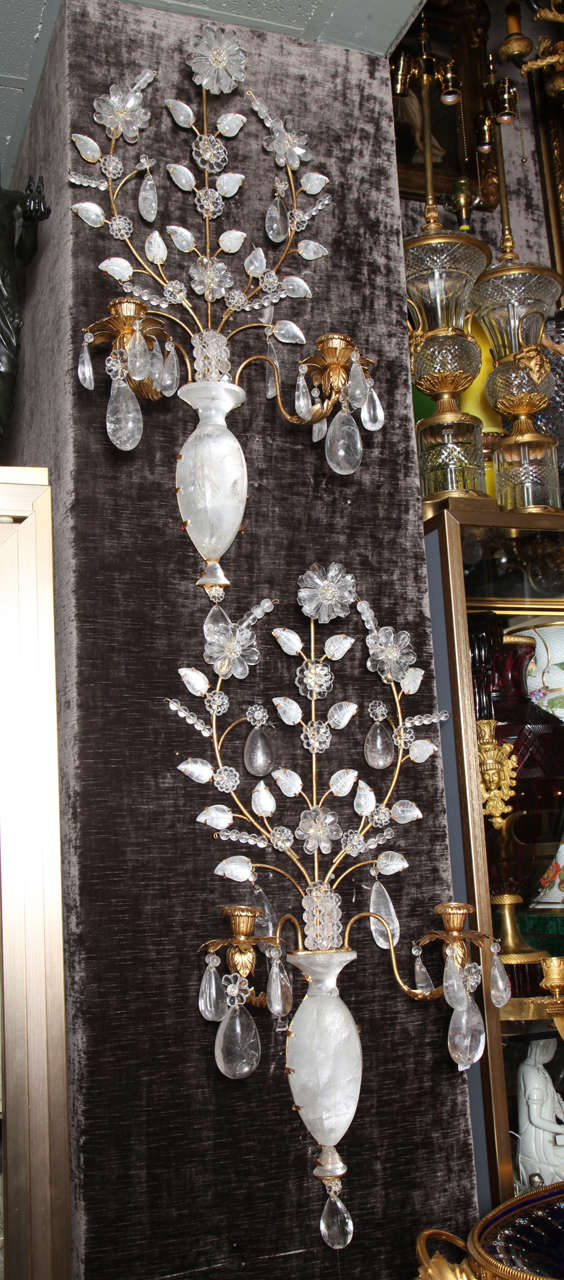 Pair of French Louis XVI style gilt bronze and cut rock crystal double light wall sconces embellished with a central cut rock crystal vase embellished with flowers and leaves, 20th century. 
Height: 31