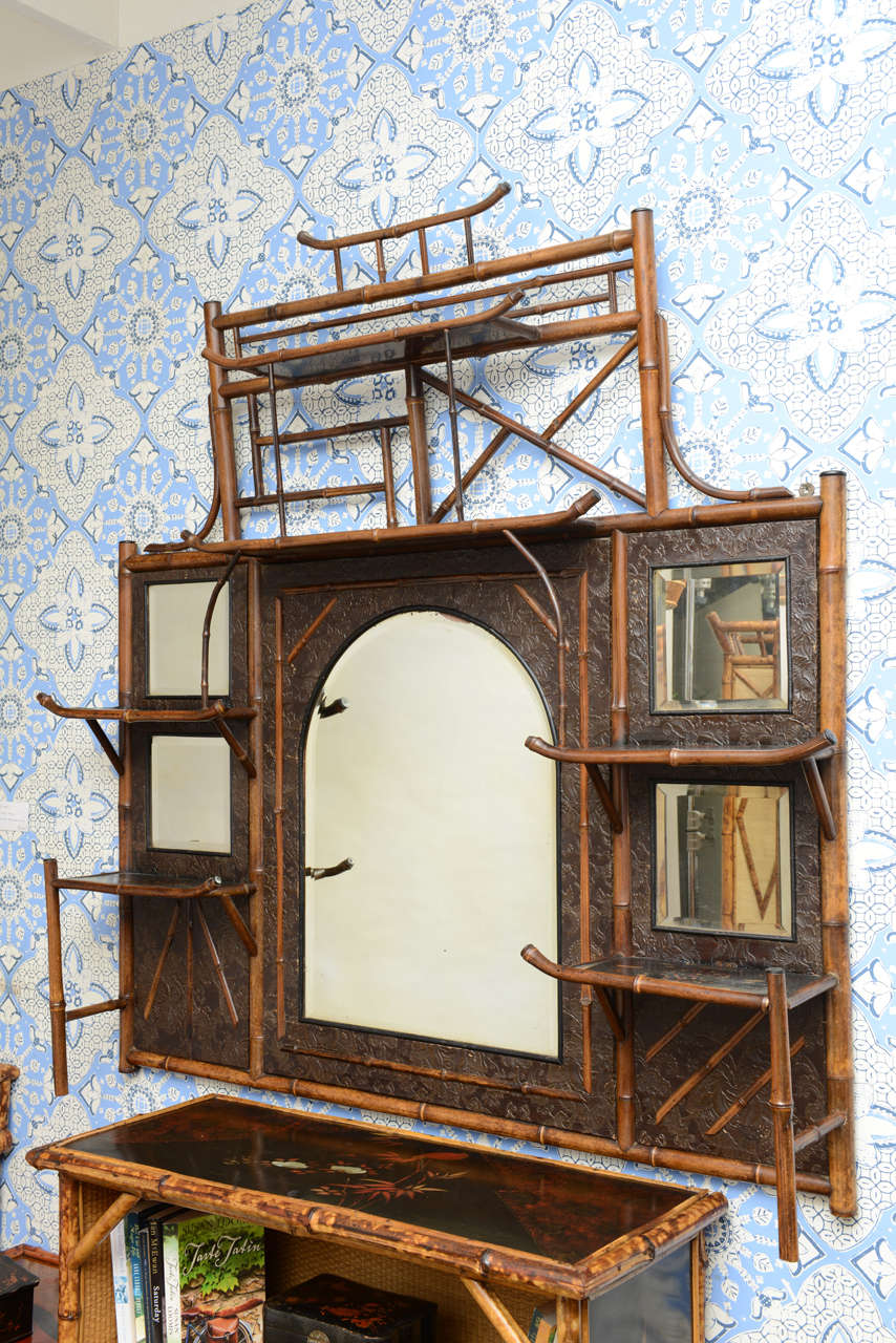 A 19th century English Bamboo mirrored and shelf, Etagere back fitted with a center beveled atrium form mirror having an embossed leather surrounded in an oriental floral motif.
Also a Mantel Mirror!