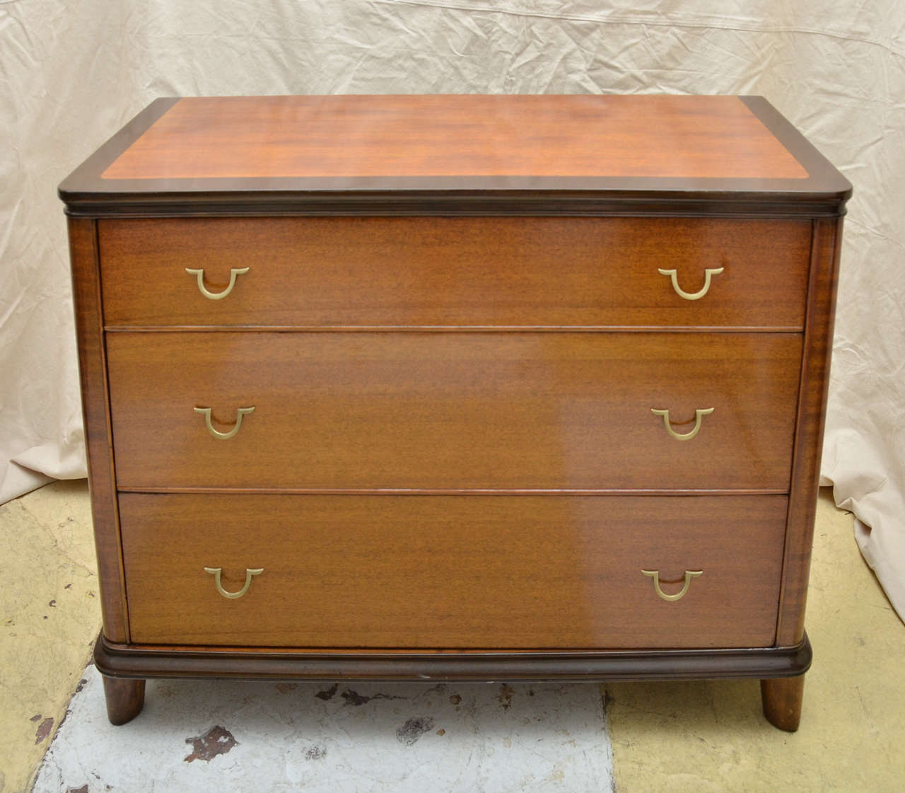 1930's American Art Deco Mahogany Commode with Dark Stained Burl Wood Banding On Top Surface And Dark Stained Legs & Moulded Base Trim. The Chest Has 3 Slightly Graduated Drawers With Brass Drop Loop Pulls. Very Stylish French Influenced Design.