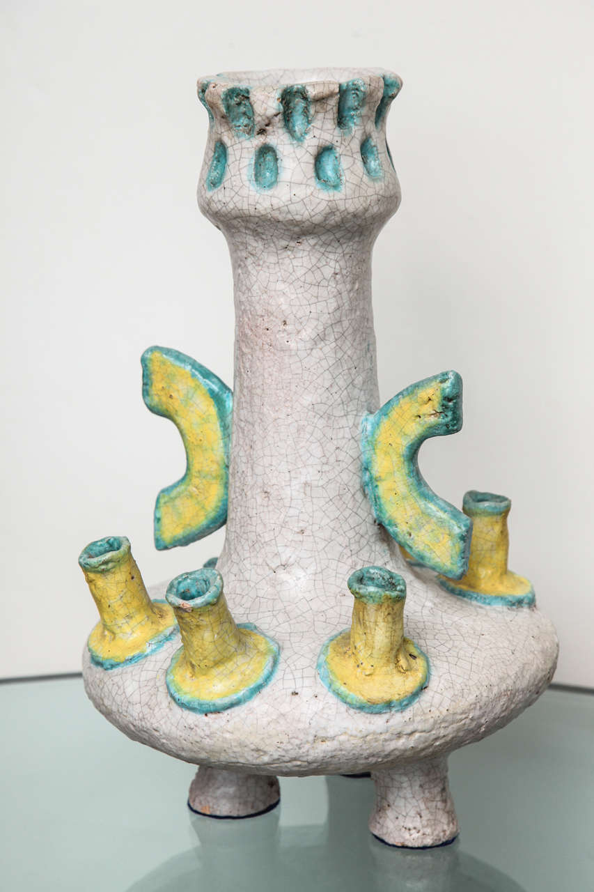 Studio made ceramic vessel with three cylindrical feet, six low spouts and applied handles to the central neck. Craquelure glazes in cream, yellow and blue.