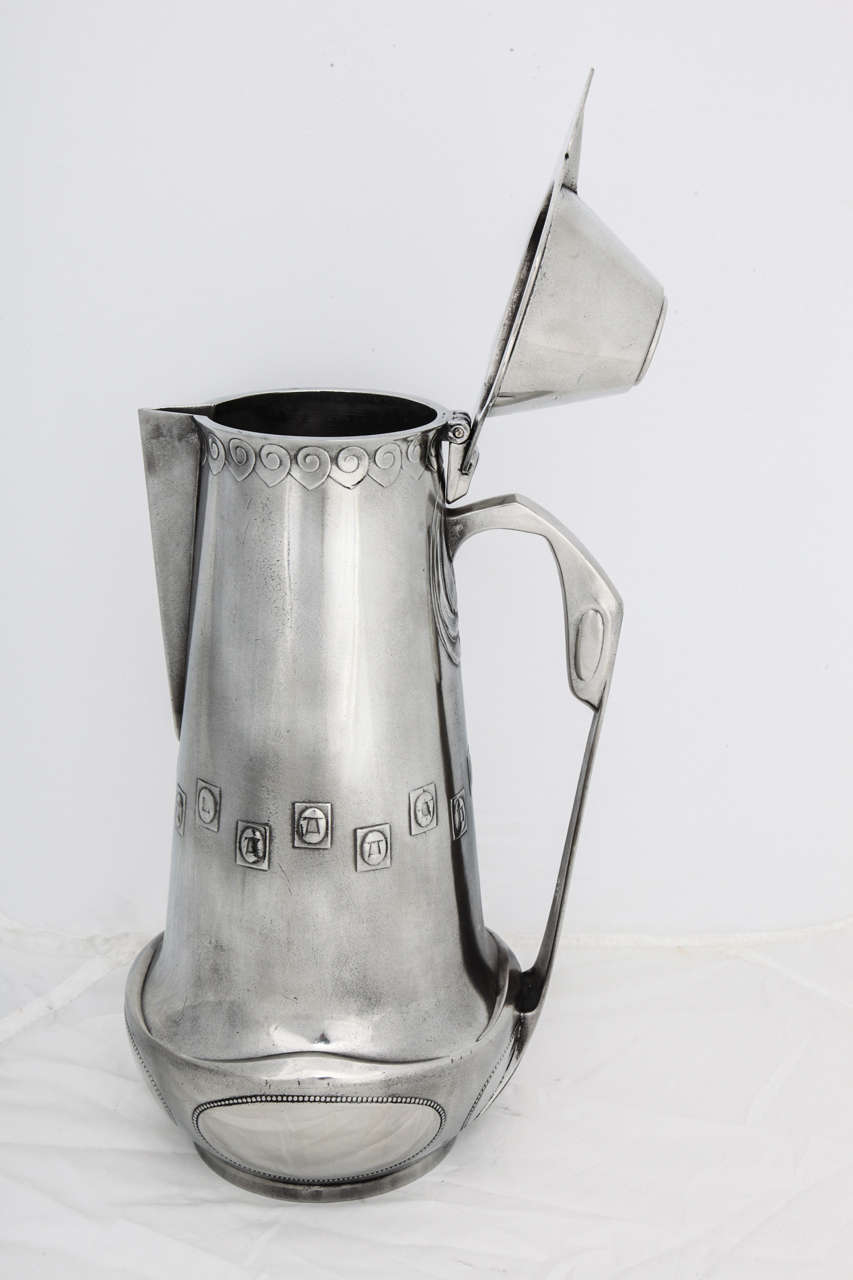 A large pewter lidded jug designed by Joseph Maria Olbrich for Eduard Hueck, 1901, Germany. The jug epitomizes Olbrich's Jugendstil Darmstadt designs.
It is marked on the underside with raised monogram, a stylized JO in a square,
the model number