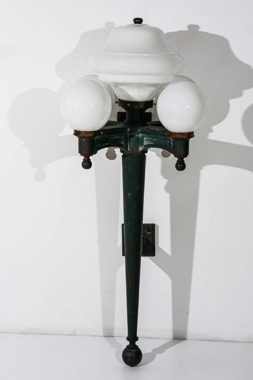 Pair of oversized five-light exterior sconces. Shades are not original to the fixture; the center shades are from the 1930s. The cast iron has been painted.