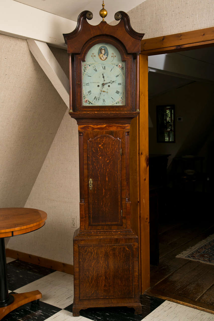Fancy for a country clock, this particular tall case clock has an impressive dial and mahogany crossbanding and inlay that dress it up in formal wear suitable for a country estate. A beautifully arched swan neck pediment on the bonnet leads the eye