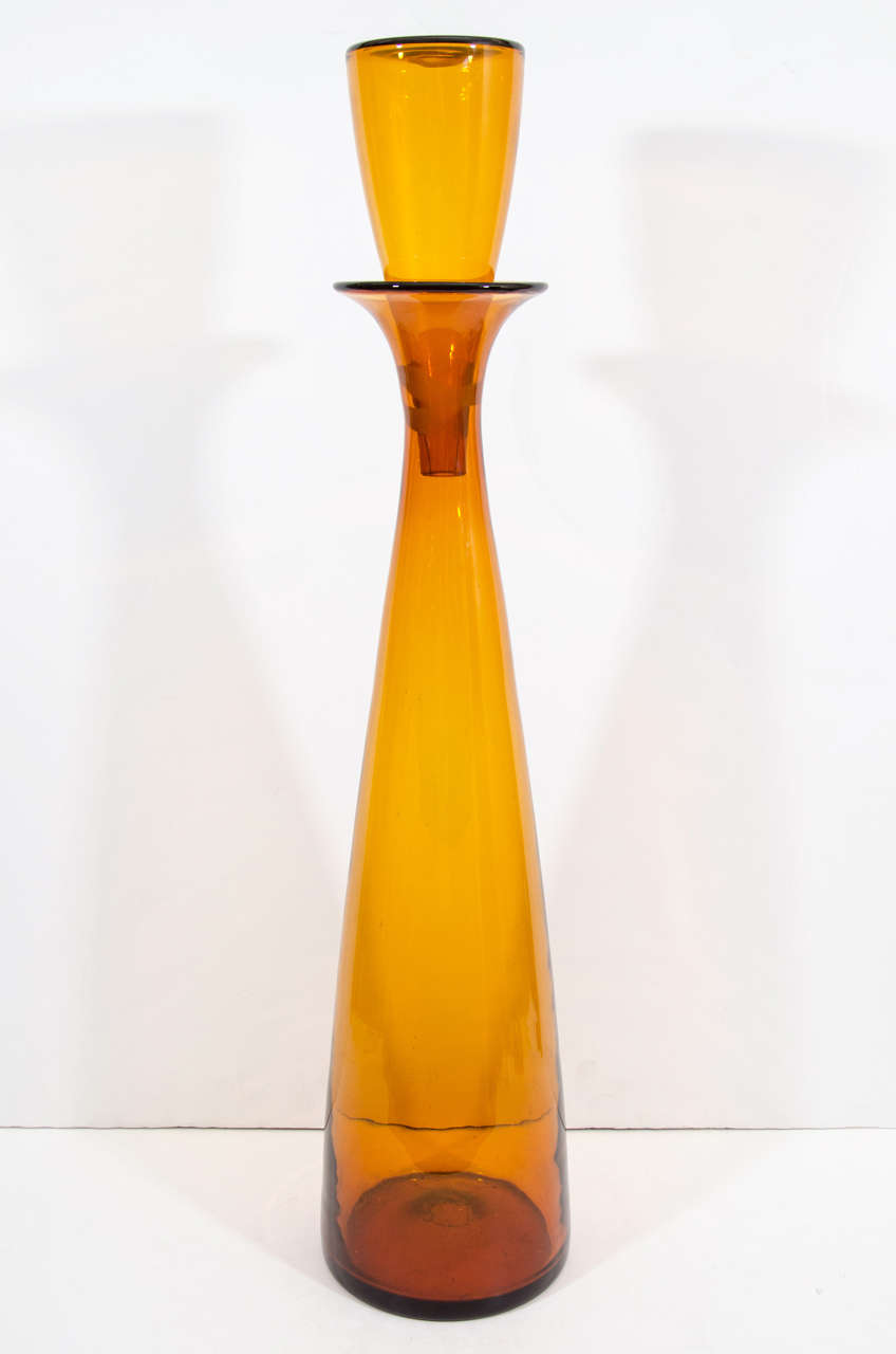 A tall amber colored glass decanter with glass stopper. The Mid Century piece is designed by Wayne Husted for Blenko Glass.

Reduced from: $950