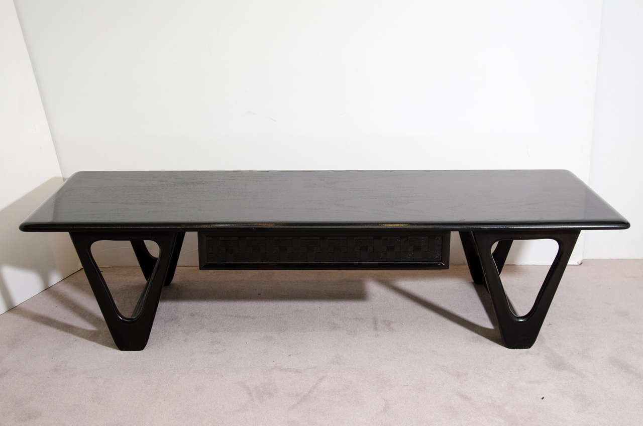 A vintage elongated coffee or cocktail table by Lane with single drawer, sculptural legs and an ebonized finish