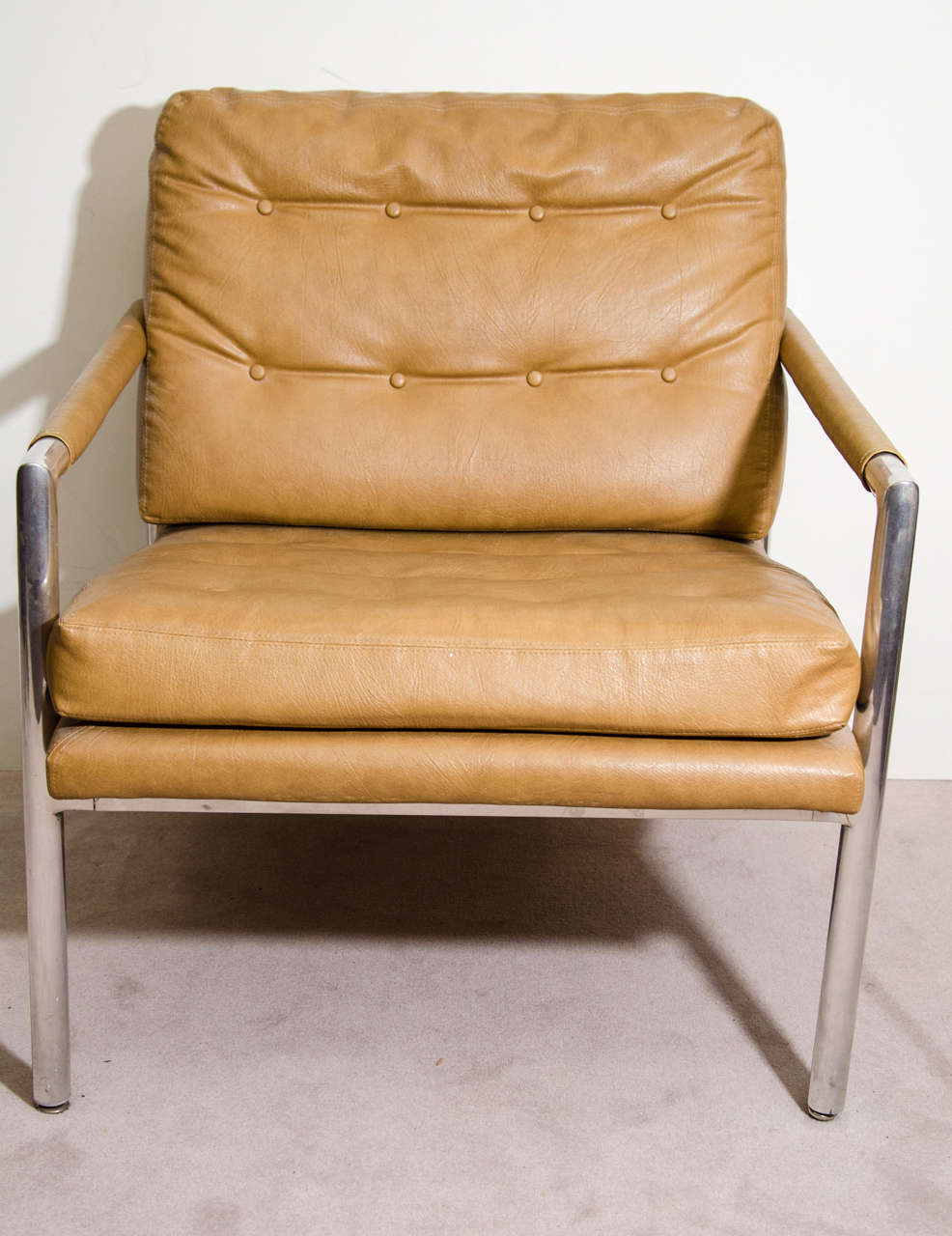 A pair of vintage Harvey Probber club chairs with aluminum frames and original tan vinyl button-tufted upholstery.