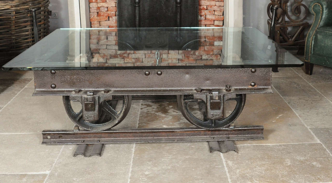 Made of an antique 19th century mine wagon. The old steel polished and waxed with an original piece of it's rails. The table top  of thick glass. Could go with steam punk items.