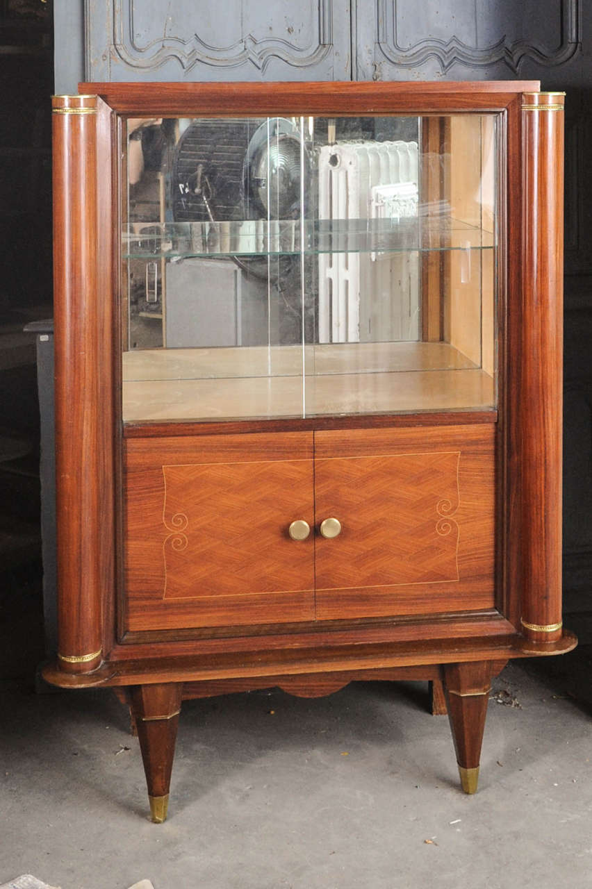 French Art Deco Cherry vitrine by Jules Leleu (1883-1961) from the 1930s and features a top compartment with two sliding glass doors and a glass shelf. A lower compartment has two wood doors with inlay marquetry and bronze fittings and keys. The