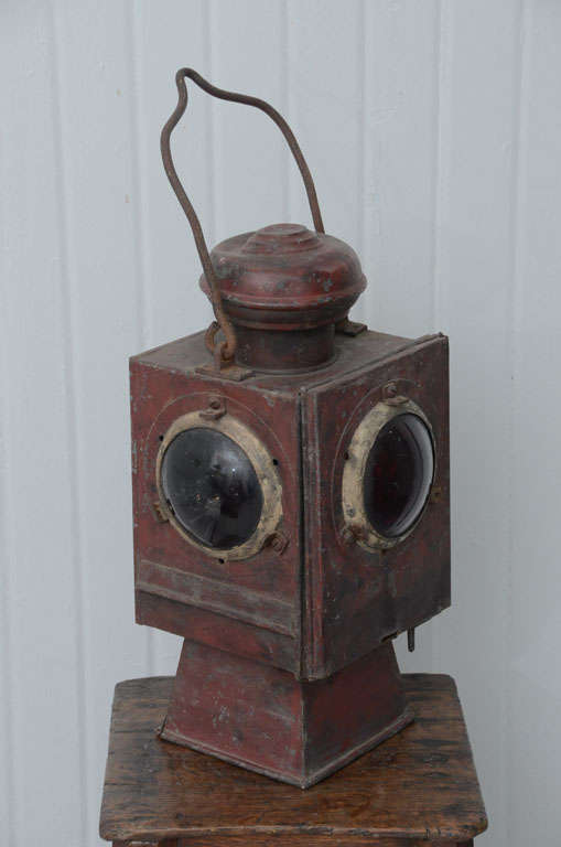 Small lantern of railway metal enamel of switchers night before. The enameled metal OBET is dark red, has a loop handle making it more stable and its acrochage a base for its illumination position above the ground. Its four sides are glass and the