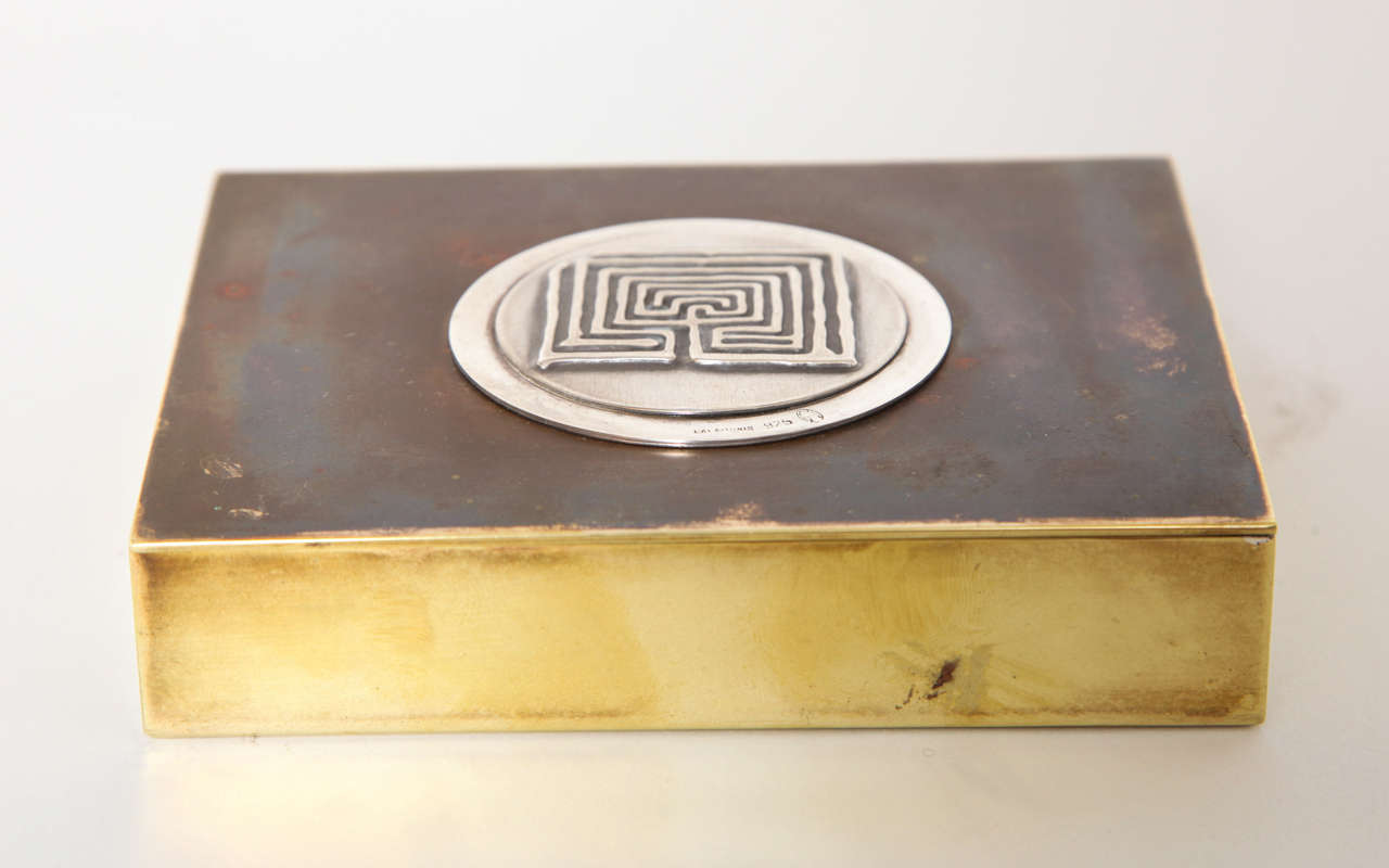 A wonderful hinged and lidded box with a sterling silver Minoan maze motif medallion on a mixed metal bronze and brass box. It is stamped Lalaounis 925  with touch mark on the silver medallion. The maze symbolizes the labyrinth that Theseus set out