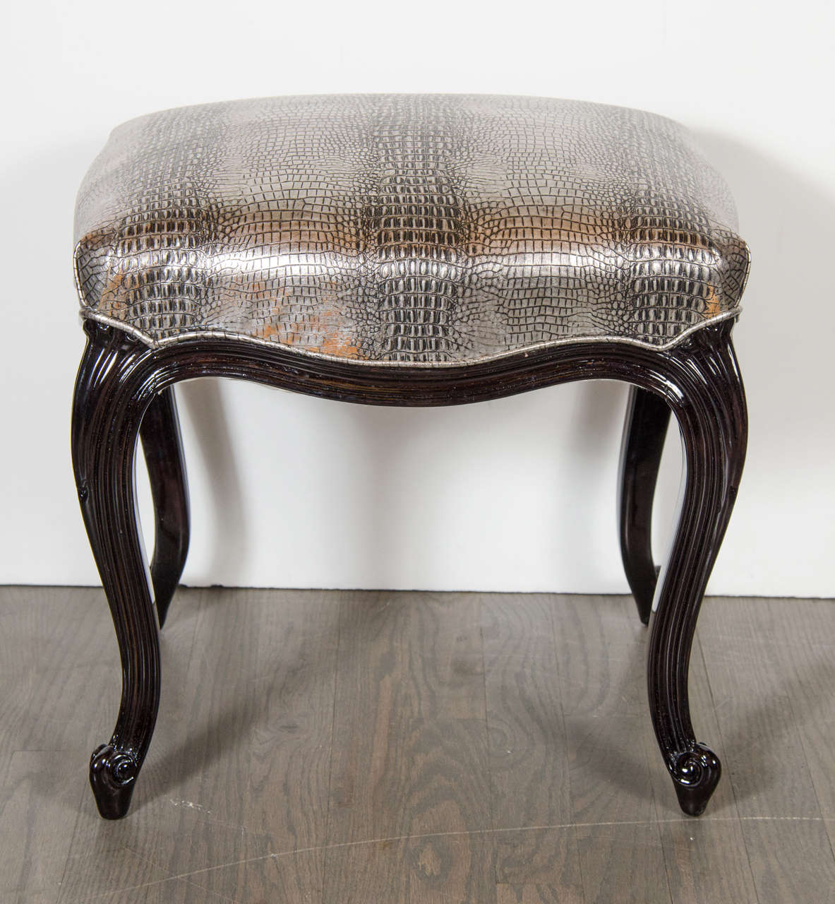 This sophisticated Hollywood Regency style stool features ebonized walnut cabriole legs paired with new metallic faux crocodile upholstery. The combination of its classic lines (recalling old Hollywood glamour) and contemporary upholstery makes this