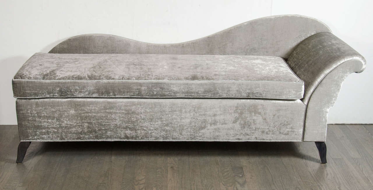 This beautiful chaise features a scrolled sleigh design that has been newly upholstered in a platinum velvet with tapered ebonized walnut legs. The piece is in restored mint condition.