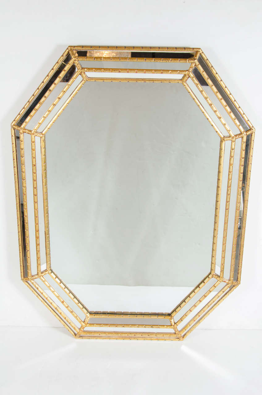 This Mid-Century Modern Mirror features a gilt octagonal frame with stylized bamboo detailing. The frame is stepped with three tiers which raises the mirror and gives it depth. It can be hung both vertically and horizontally and is in excellent