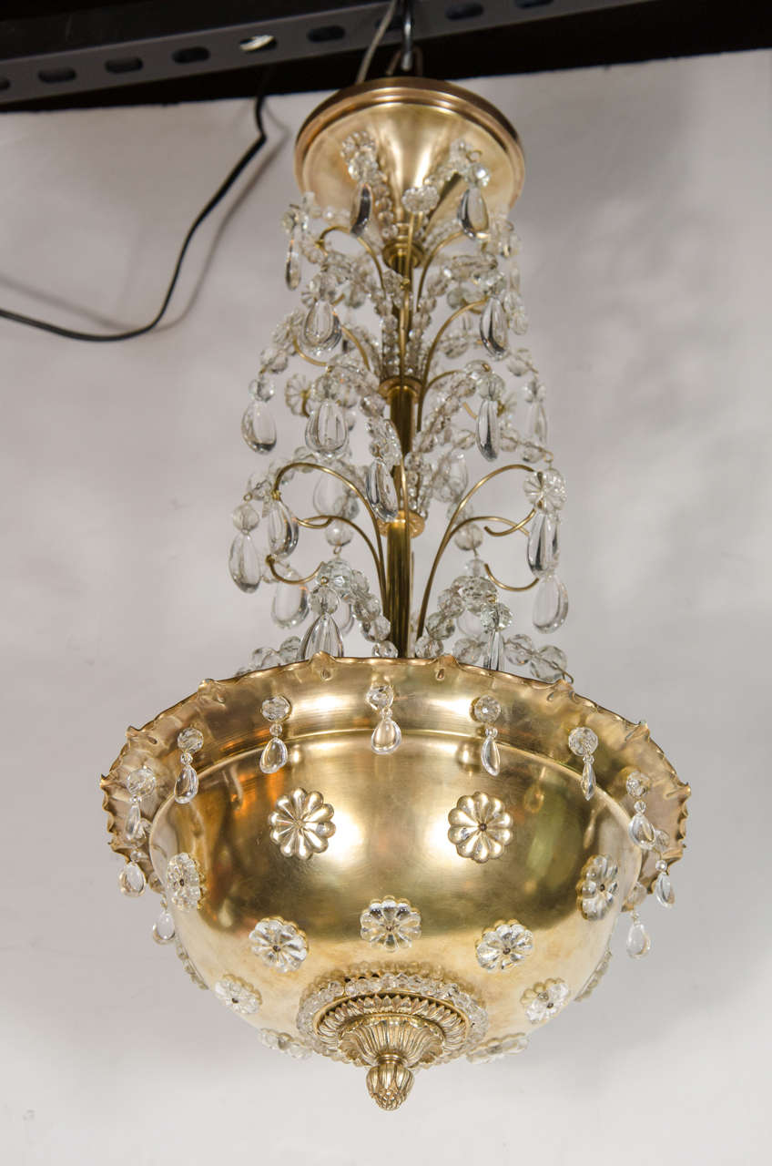 This gorgeous chandelier features a brass globe and fountain design fitted with tear drop crystals and crystal rosette ornamentation. It is fitted with four bulbs and the light streams through the crystal ornamentation. This piece has newly rewired