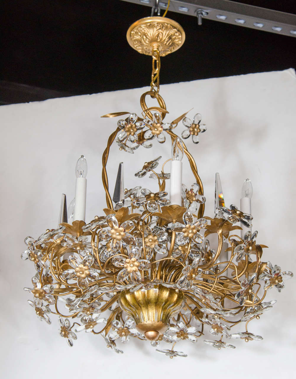 This stunning chandelier has a gilded brass cage bouquet frame adorned with fine cut crystal flowers throughout. It is fitted with six candelabra bulbs and six cut crystal spears. The bottom canopy fitting is in gold Murano glass. This chandler can