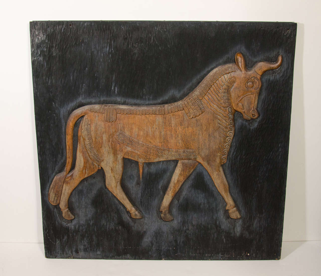 Rare artwork featuring Arabic bull in hand-carved reclaimed wood with exquisite attention to form and detail. Highly stylized engraved bull with decorative carvings over wood panel with hand chiseled grooves throughout. The bull has tones of faded