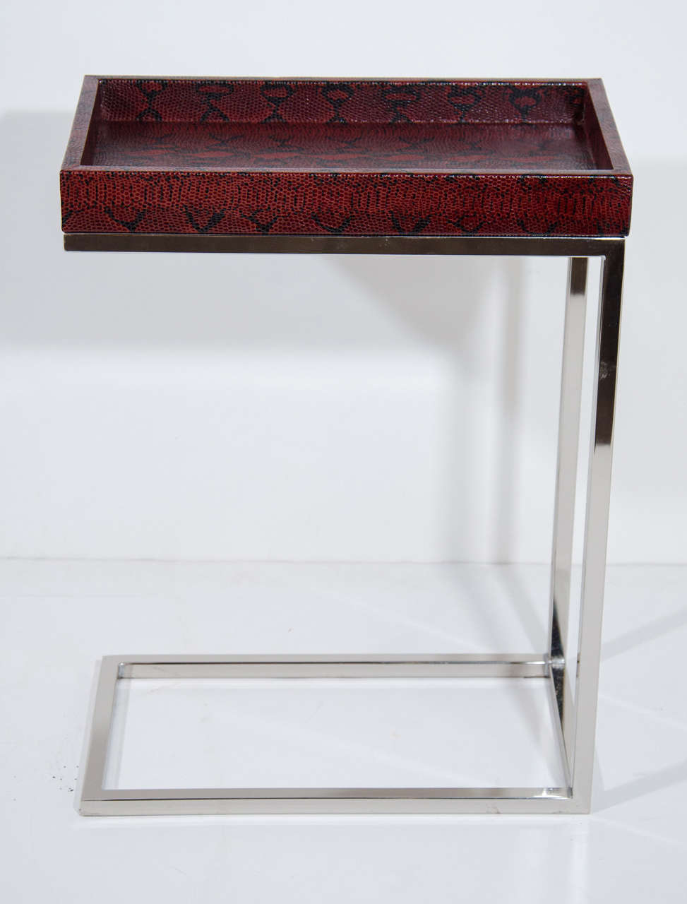 Modernist drinks table or side table with cantilevered base design in chrome, and with an embossed leather tray top with python print in garnet red.  Removable top functions as a serving tray.