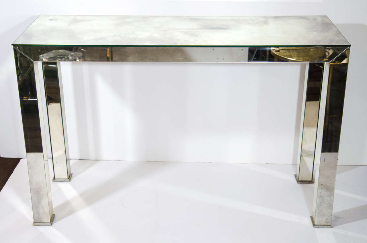 Mid century modern mirrored console table or sofa table. The table is comprised of mirrored glass with smokey details and has wood trimmed legs in a silver leaf.
