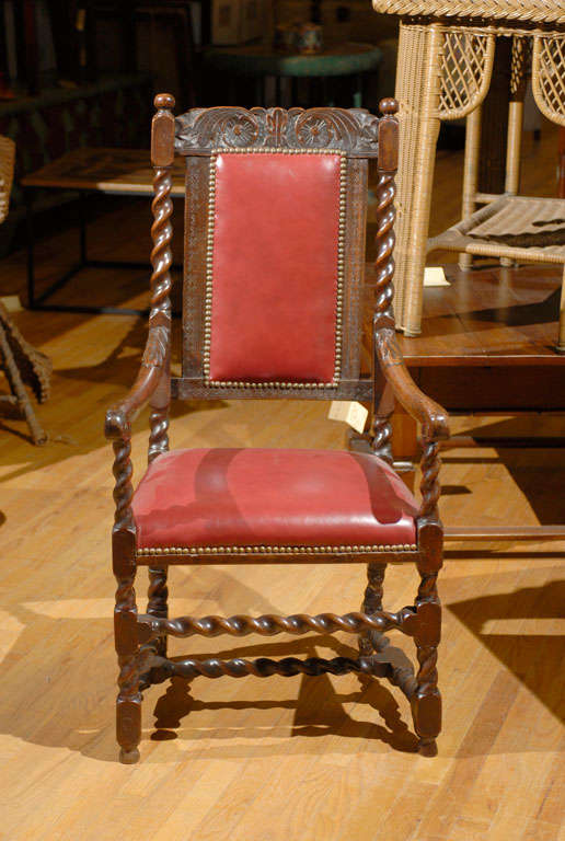 This is handsome carved chair.   The legs and supports are barley twists which are often a design element from England.  Barley twists are not the only main design; the head rest is also beautifully carved.   The red leather upholstery compliments