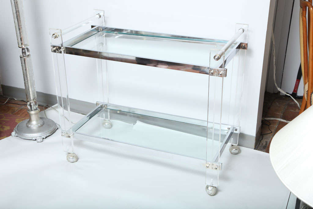 A fabulous 'invisable' bar cart. A glass shelf and mirrored shelf sit on a lucite and chrome body.