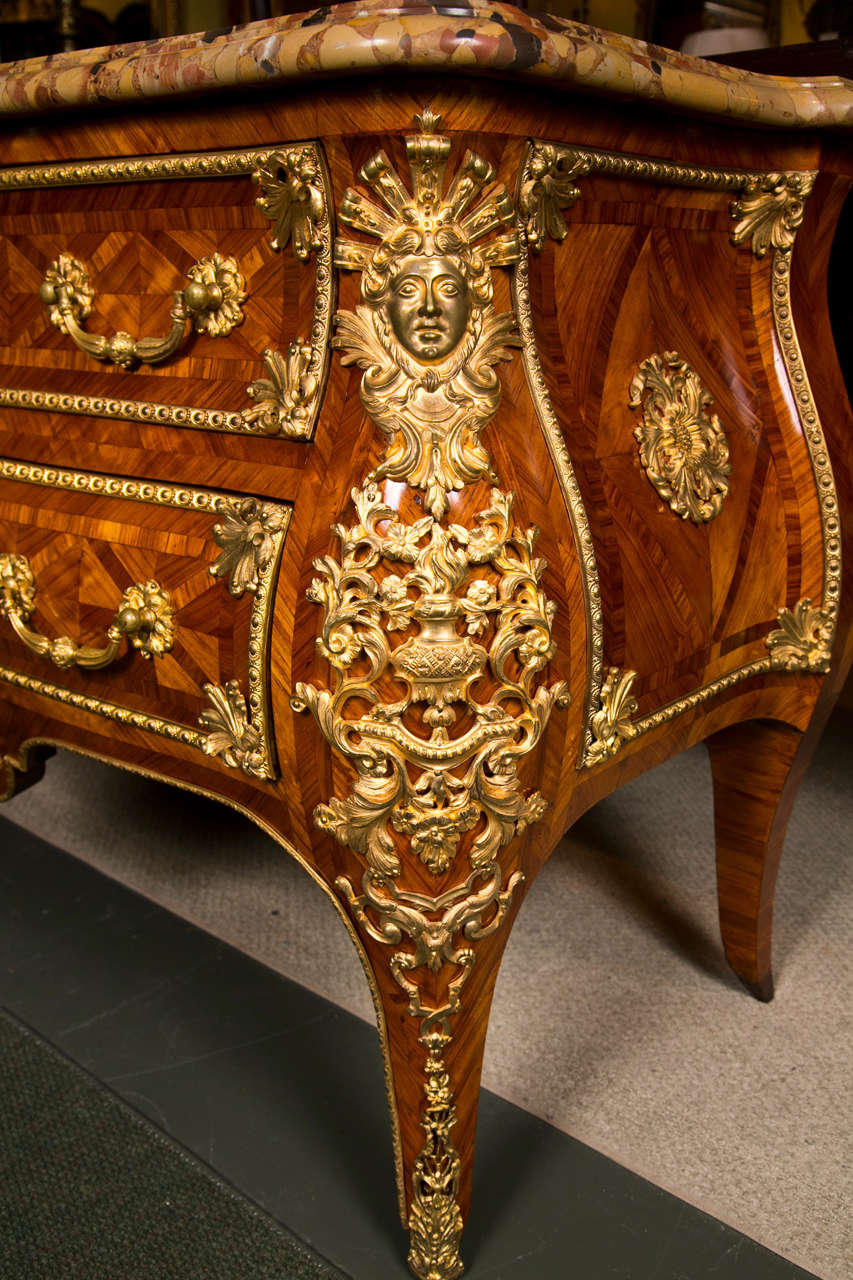 A Continental sculpted breche d'Aleppe marble set upon a stately bronze dore mounted tulip and kingwood parquetry, two-drawer chest in the Louis XV style.  The workmanship is of the finest and equal to the likes of Linke, Sormani and Dasson..