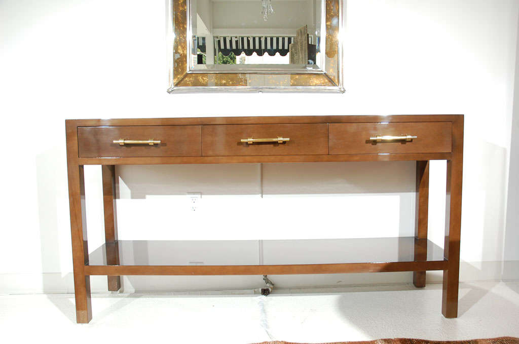 A striking custom three drawer console table with bottom tier designed by William Haines for the Bel Air estate of F. Hugh and Mary Herbert.  This piece features three stylized bronze drawer pulls and is constructed out of solid maple with new high