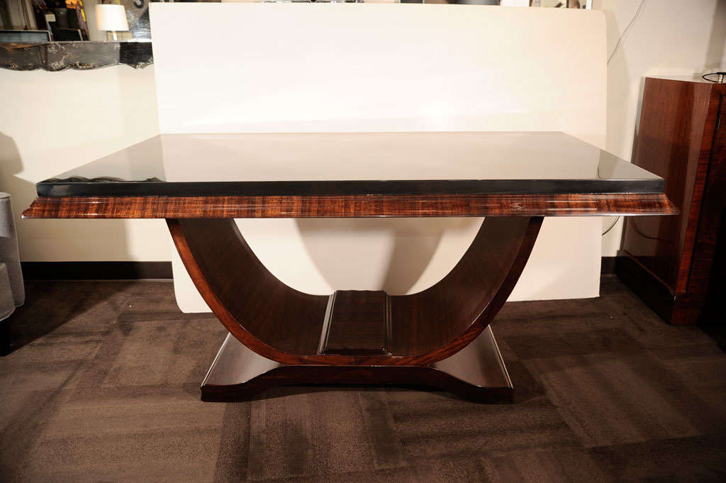 Spectacular Art Deco dining table<br />
with stylized pedestal base, in<br />
book matched mahogany and<br />
black lacquer top.  The table<br />
also includes two - 18