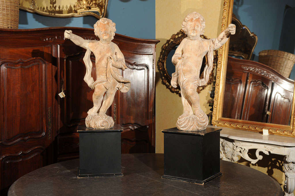 LARGE ROCOCO CARVED WOOD PUTTI ON PAINTED SQUARE PLINTHS.