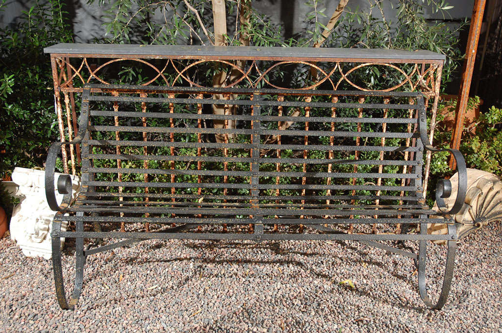 A lovely iron bench with slender iron slats, a shaped seat and scrolled arms. Now painted black.
