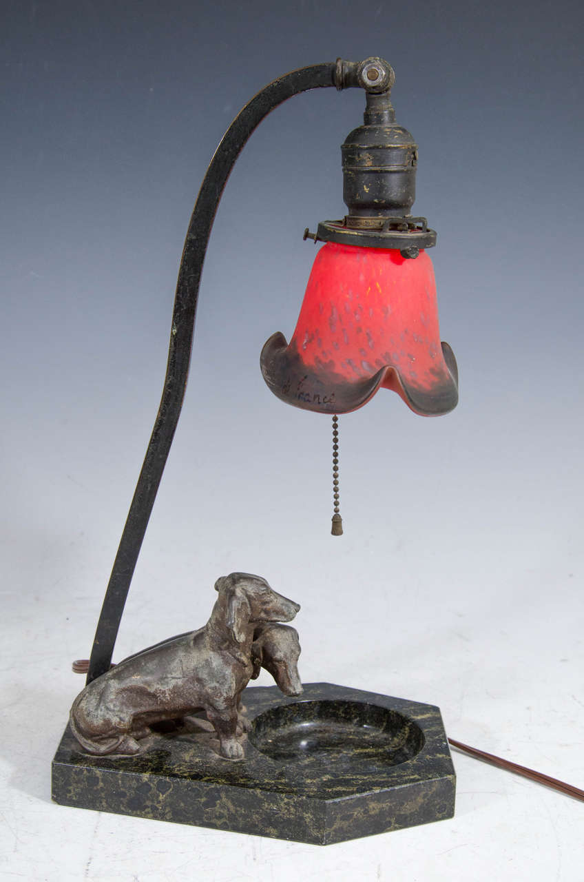 A rare charming antique table lamp with two adorable bronze dachshunds on a marble base with a glorious red art glass shade. Lamp has been rewired. It retains its original antique pull switch.

Measurements: 16