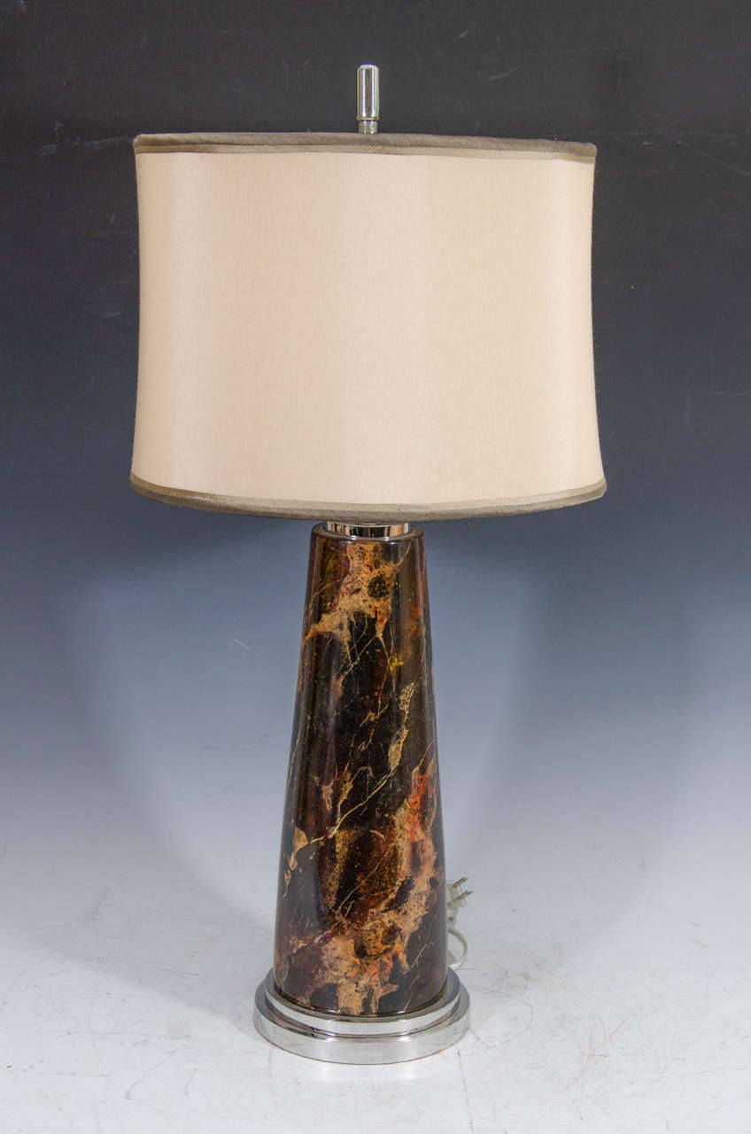 A contemporary table lamp in faux tortoise-shell with a chrome base, and a silk shade.