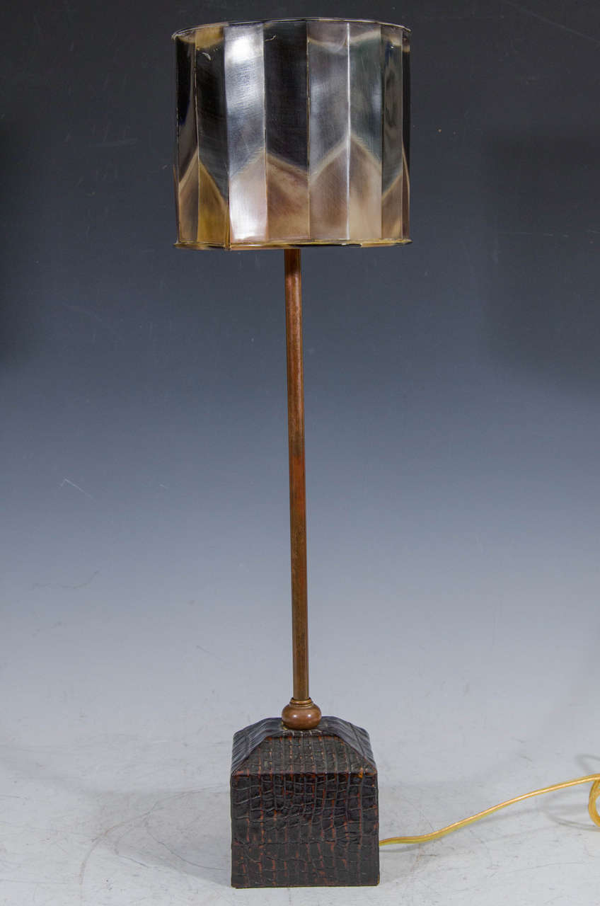 A contemporary table lamp with metal stem, faux crocodile base, and faux tortoise-shell shade.

The shade is in as is condition. It has a few scratches and there is splitting at several seams.