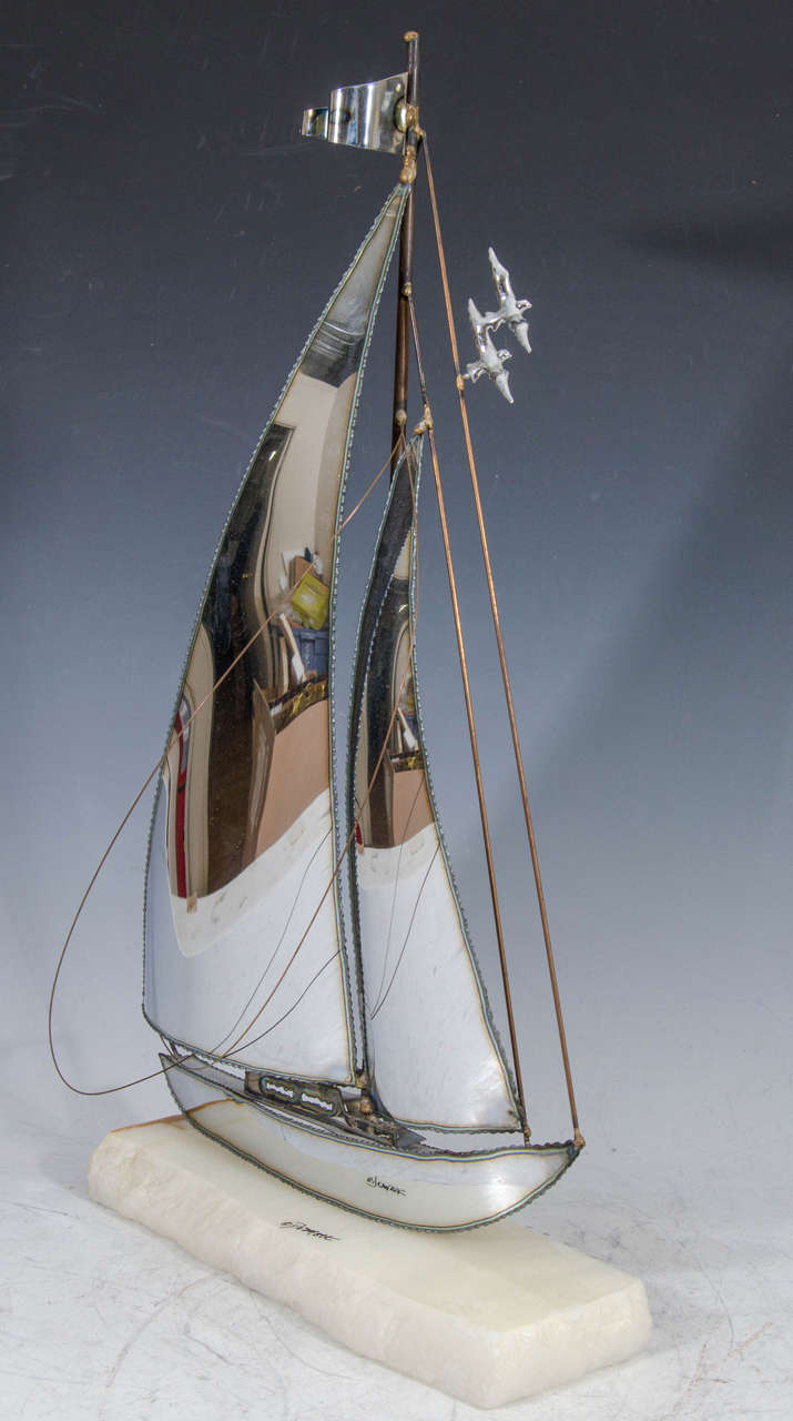 A vintage burnished metal sailboat sculpture on a quartz base signed DeMott.