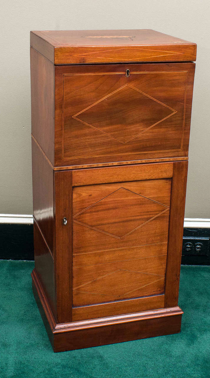 This unusual piece has a lift top to the large upper section. The lower section opens by door (with key) and has one shelf inside. Lined interiors, great patina, excellent inlay and pine back.