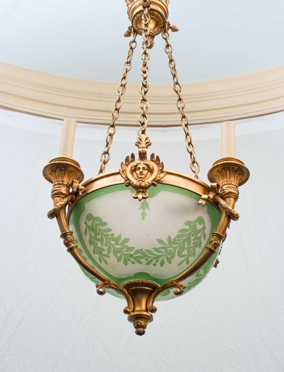 This high style fixture with neoclassical detail has a total of six lights, three on candle arms on the outside and three lights inside the bowl. Original frosted glass bowl with pale green applied decoration. Total height can be reduced by removing