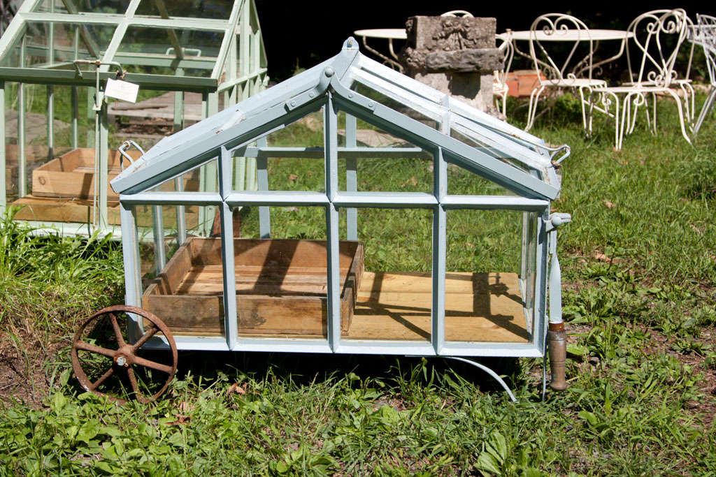 Reminiscent of the Edwardian era of gardens, this handmade portable greenhouse in robin's egg blue paint is ideal for year-round gardening!  With its antique iron wheels, wooden handles, recycled pine floor, and a seed tray stenciled 