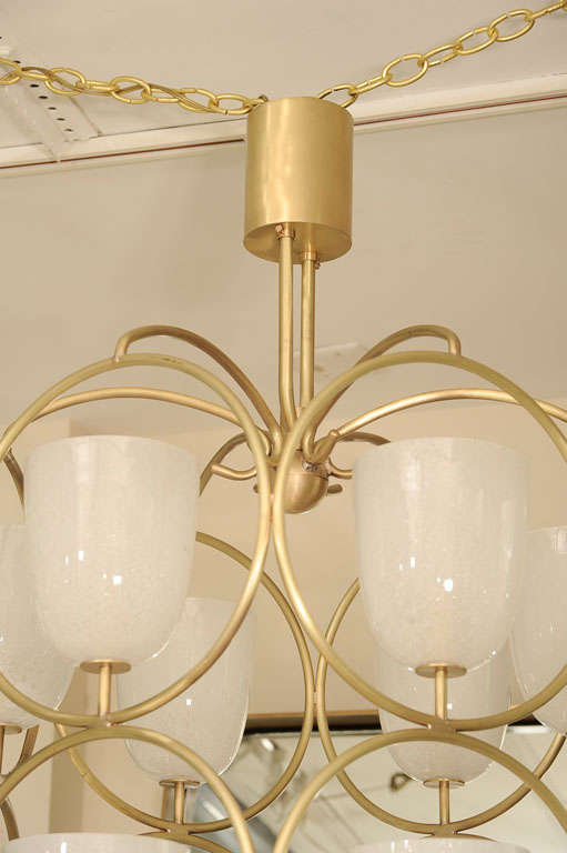 Large scale brass chandelier composed of multiple circular elements containing white glass shades.