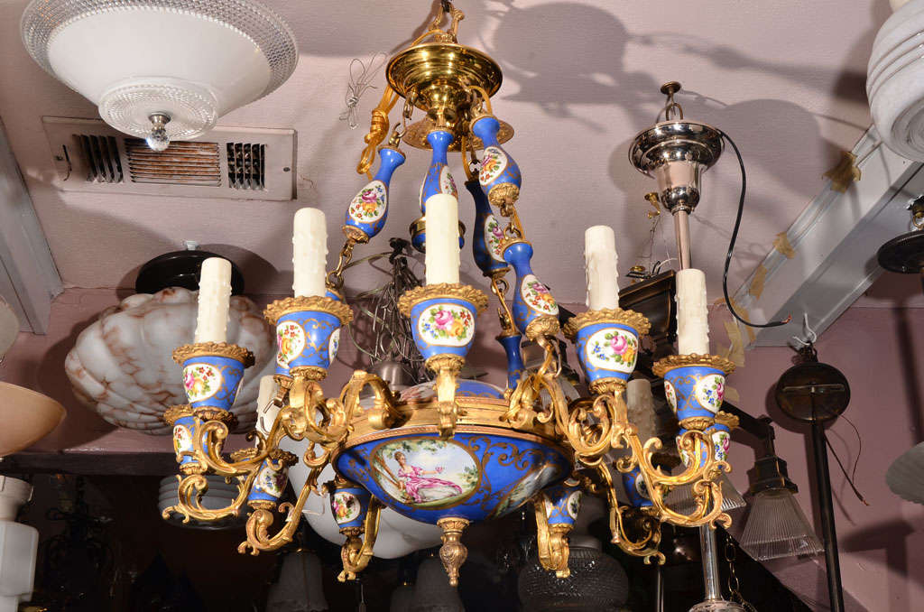 Chandelier with 12 gold ormolu candle arms in Louis XVI, Sèvres porcelain style. The Serves style scenic medallions are beautifully painted, top and bottom bowls of the fixture, with four supporting chains of painted porcelain links separated with